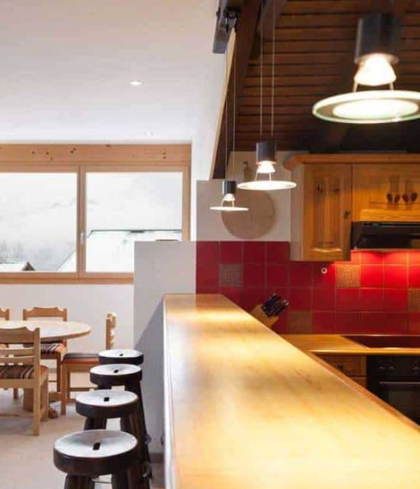 Dark Rustic kitchen with bar stools and a bright dining area in a comfortable chalet